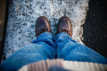 Top view of brown shoes or boots footprint wear by male adult and jeans during snow or winter season.