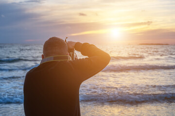 Man taking photos on a tropical beach during sunset. Holiday vacation and travel concept.