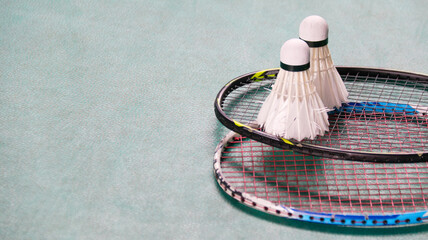 White badminton shuttlecocks and badminton rackets on green floor indoor badminton court soft and...
