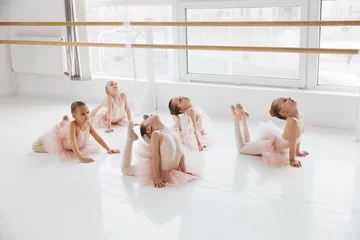 Crédence de cuisine en verre imprimé École de danse Group of little girls ballerinas doing floor stretches in a bright modern dance studio. Classical ballet school. Concept of art, sport, education, hobby, active lifestyle, leisure time.