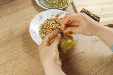 Woman hands preparing wrap stuffed with rice ingredient. Greek or Turkish food Yaprak Sarma or...