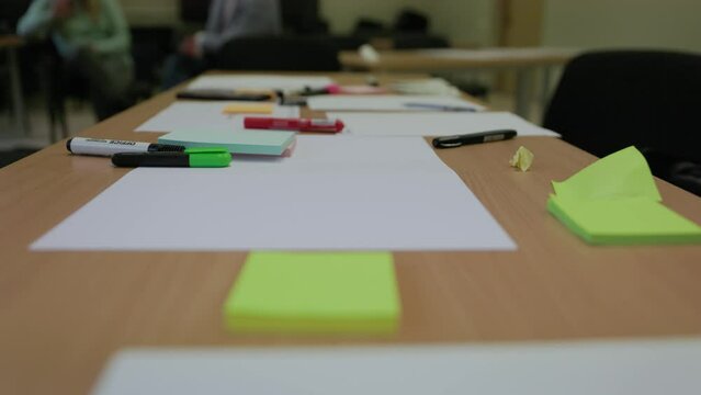 Office school table covered with paper and markers for creative idea generation in slow motion