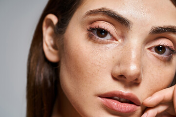 A close-up of a young Caucasian woman with mesmerizing brown eyes and clean skin in a studio setting.