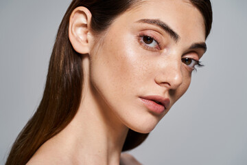 A young Caucasian woman with long brown hair and brown eyes exudes grace and charm in a studio...