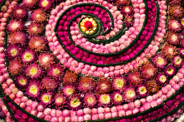 A flower arrangement with a spiral design. The flowers are pink and yellow. The arrangement is very colorful and eye-catching