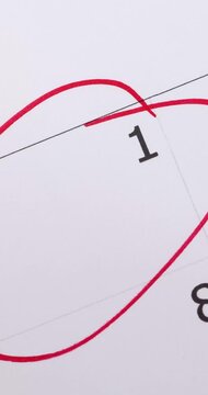 Portrait video footage of calendar showing the number 1 with a males hand circling the date with a red pen, save the date or appointment reminder concept.