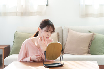 鏡を見て肌のチェックをするミドル女性（美容・スキンケア）