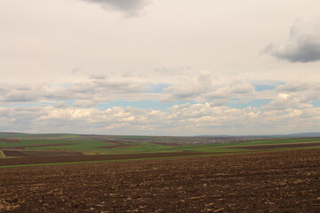 A landscape with a field and clouds