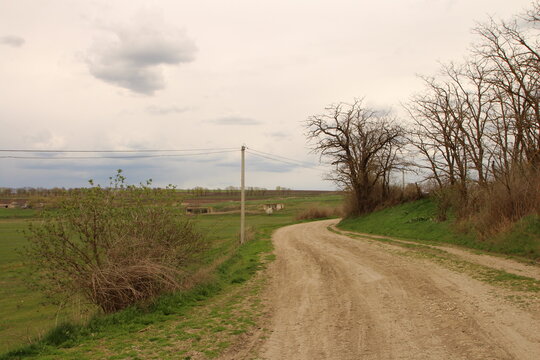 A Dirt Road With Grass And Trees On Either Side Of It