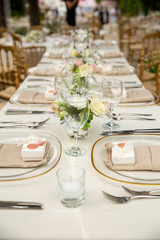 White color wedding table decorated with decorative and elegant for wedding. There are flowers, candles and serving plates on the wedding table.