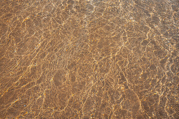 sandy beach with waves rolling in, creating a beautiful natural background. beige sand contrasts with ocean waves. concept for perfumes, smells, heat, freshness, coolness and other associations