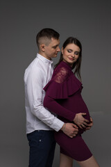 pregnant couple on a grey background close up, fashion pregnant model posing in studio, pregnant woman stands on a grey background, studio shoot