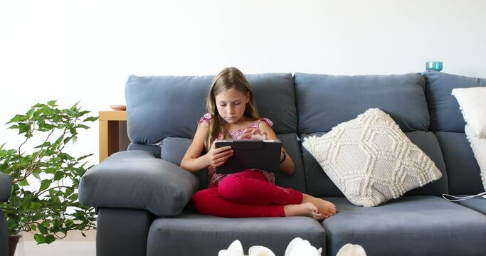 Girl sitting on a sofa at home using a tablet