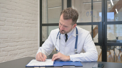 Fototapeta premium Middle Aged Doctor Working on Documents in Clinic