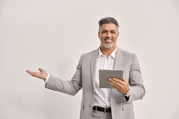 Happy mature business man using digital tablet isolated on white background. Middle aged ceo executive wearing suit, older businessman professional pointing showing aside presenting ads at copy space. - 777390681