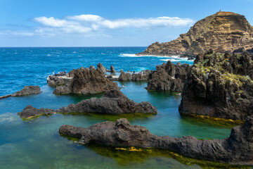 Tourists visiting the natural seawater lava pools in Porto Moniz, Madeira island, Portugal - 777391802