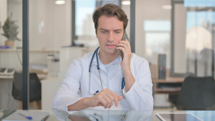 Male Doctor Discussing Treatment with Patient on Phone