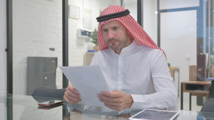 Middle Aged Muslim Man Reading Business Report at Work