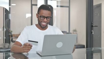 Young African Man Shopping Online on Laptop in Office