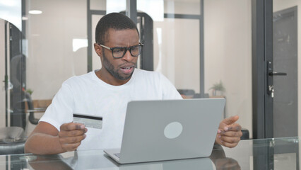 Young African Man Upset with Online Shopping Failure on Laptop - obrazy, fototapety, plakaty