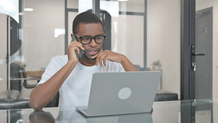 Young African Man Talking on Phone at Work