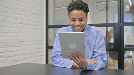 Young African Woman Celebrating Online Success on Digital Tablet