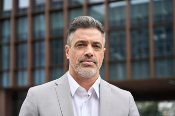 Portrait of confident rich 45 years old middle aged man business owner, mature company ceo executive, Latin investor wearing suit standing outside office on city street looking at camera. Headshot - 777402220