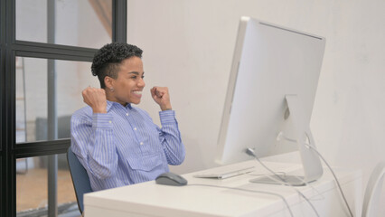 African Woman Celebrating Success on Desktop Computer