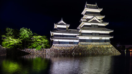 Old Japanese castle at night with reflection in its moat (Matsumoto Castle) - obrazy, fototapety, plakaty