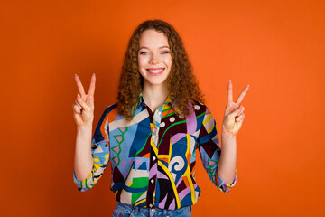 Photo of lovely pretty cute girl wear trendy print clothes v-sign isolated on vivid orange color background