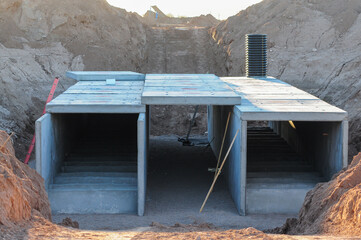 Precast concrete box culvert structure under installation in excavation site, illustrating...