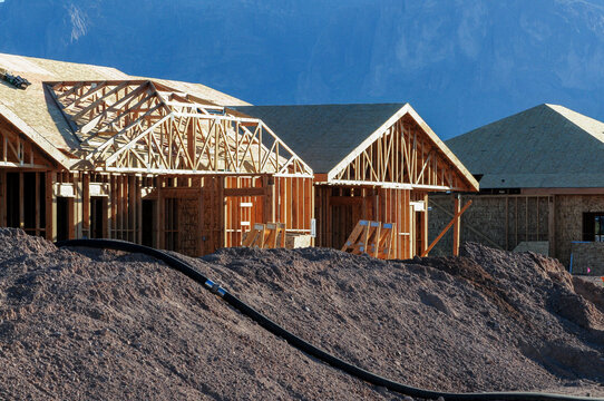 Dirt mounds surround the wooden structures of homes under construction at a new subdivision in Pinal County, Arizona.