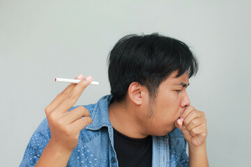 Smoker holding a cigarette suffering from chronic cough, Asian man patient coughing with...