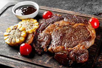 A succulent grilled steak, accompanied by roasted vegetables and a savory sauce, artfully presented on a rustic wooden board. A feast for the senses