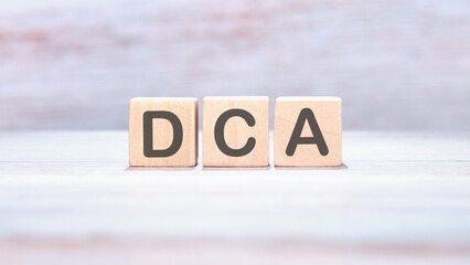 Dollar cost averaging DCA text on wooden cubes on an abstract background