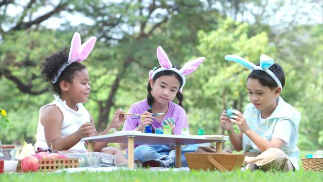 Happy family enjoying a picnic in the park, Children sitting and coloring their beautiful Easter eggs.