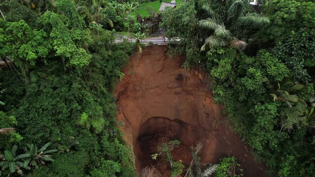 Aerial view of local landslide at steep slope of forested ravine, camera fly away, reveal wide view of land around incident location. Natural disaster at countryside at north of Ubud town