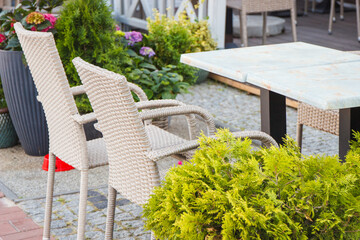 Wicker chairs and tables on fresh air in outdoor restaurant or cafe