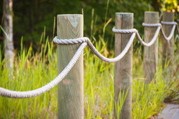 Closeup of fence made of rope and wooden pole in park