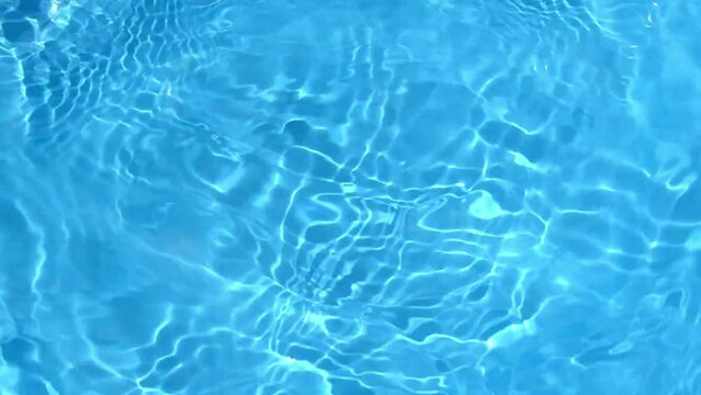 Natural pure blue water surface background. Soft water waves with light reflections. flowing ripples in slow motion. 4K shot for cosmetic and design advertising