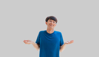 A young Asian man in his 20s wearing a blue t-shirt acts in a relaxed manner isolated on a gray...