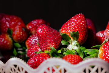 fresh strawberries in pink bucket on black background