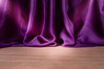 Empty wooden floor with Elegant wavy purple satin cloth curtains, defocused in the background