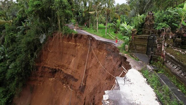A unique aerial perspective of results of dangerous landslide. Road broken, unstable ground fall down to ravine, buildings in high risk. Small earthquake and heavy rains aftermath at central Bali