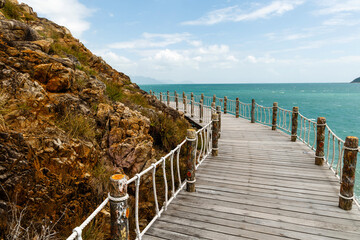 A wooden walkway runs along the beach and mountainside