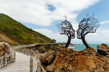 Wooden path along the sea and trees in the form of silhouettes of faces
