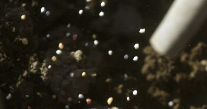 Super slow motion close up of natural bio fertilizers granules added for field ground soil by agricola machinery before plant in ecological rural farmland agricultural plantation at 1000 fps