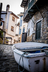 Vintage fishing skiff, white and blue, at the doorstep of traditional stone homes.