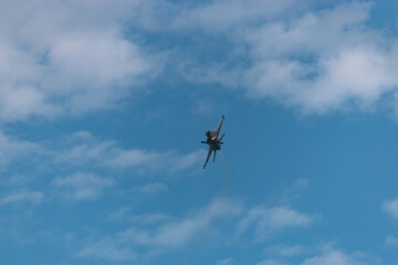 F-16 fighting military fighter jet airplane flying against blue sky background.