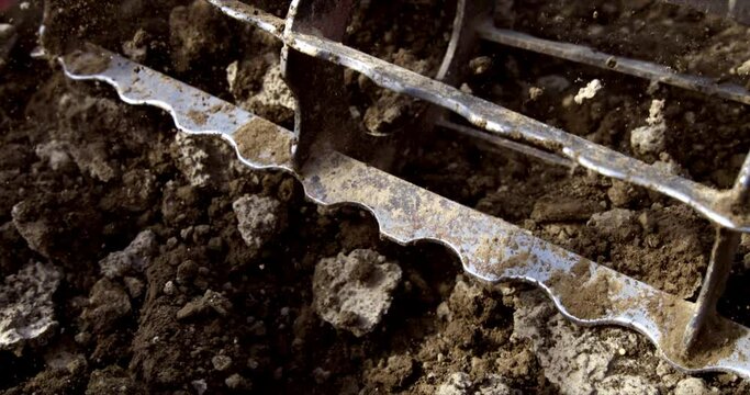 Super slow motion close up of agricola machinery tractor with disk plow harrows cultivates field and prepares land soil for sowing in ecological rural farmland agricultural plantation at 1000 fps.